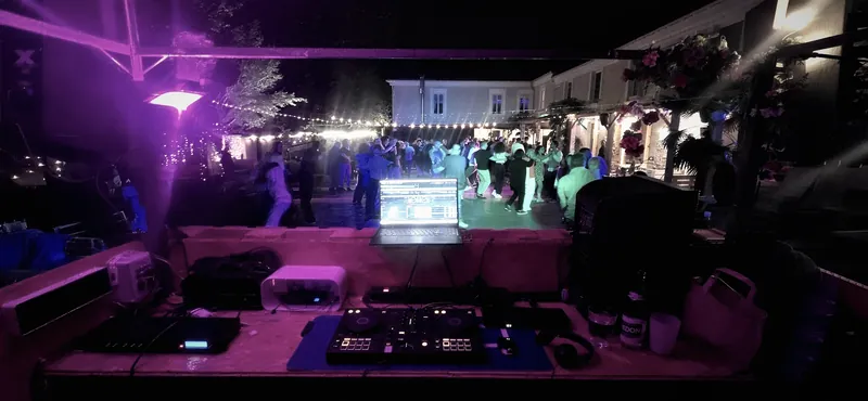 Piste de danse pleine sous les lumières roses, vue depuis la cabine du DJ.