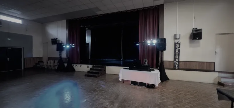 Salle des fêtes avec scène, enceintes et éclairage installés.