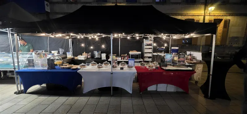 Le stand sous guirlandes lumineuses, vu de face, à la tombée de la nuit.